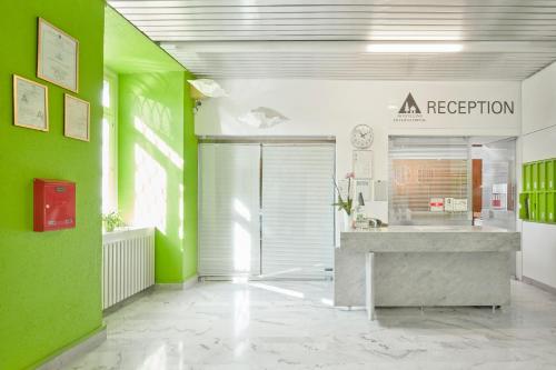 a room with green walls and a reception counter at Ostello Montebello - Bellinzona Youth Hostel in Bellinzona