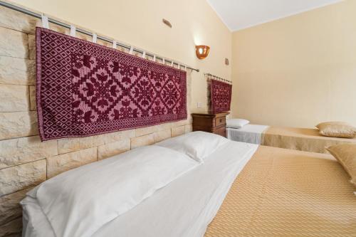 a bedroom with two beds and a red rug on the wall at Sa Funtana in Gonnesa