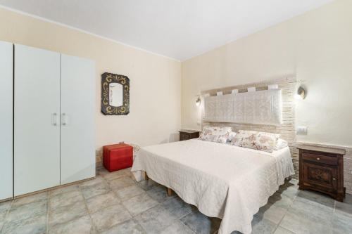 a bedroom with a white bed and a red suitcase at Sa Funtana in Gonnesa
