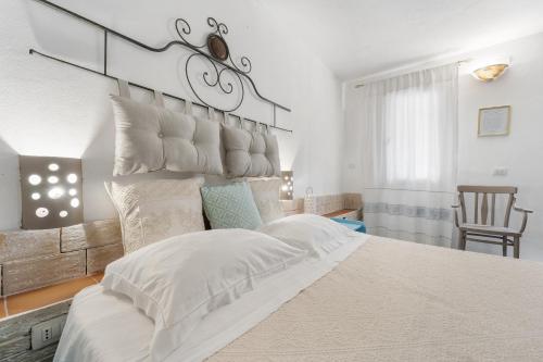 a white bedroom with a large bed with white pillows at Sa Funtana in Gonnesa