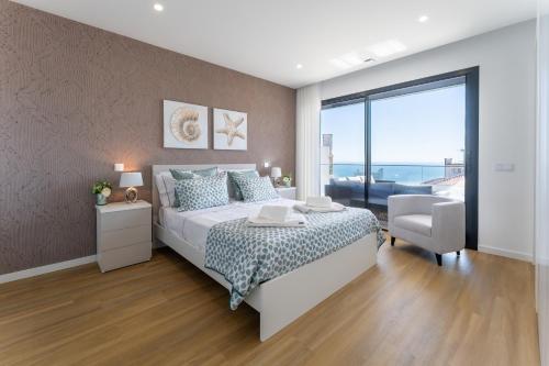 Un dormitorio con una cama y una silla y una ventana. en T3 Mar de Prata, en Nazaré