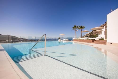 a swimming pool with blue water and palm trees at Servatur Hartaguna - Adults Only in Puerto Rico de Gran Canaria