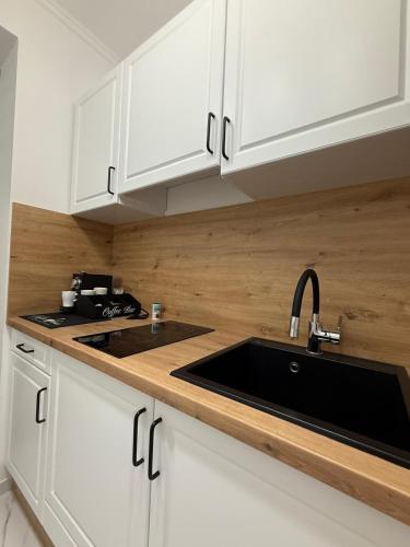 a kitchen with white cabinets and a black sink at Harmony Suite Apartment in Pápa