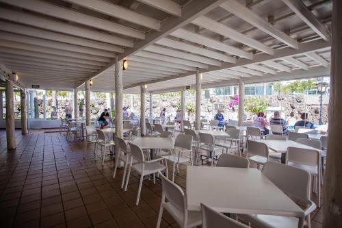 a restaurant with tables and chairs and people in the background at Servatur Waikiki in Playa del Ingles