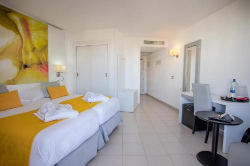 a hotel room with two beds and a table at Servatur Waikiki in Playa del Ingles