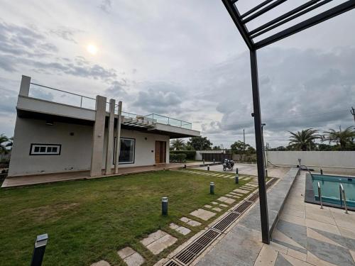 a house with a lawn in front of it at Bluewater Farms 2BR Villa with pool by Homeyhuts in Hyderabad