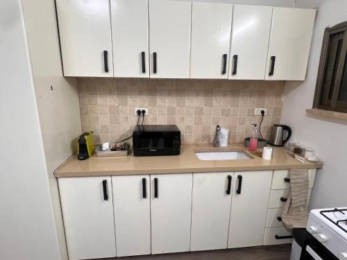 a kitchen with white cabinets and a microwave at בית הקונגרס גבעת אולגה in H̱adera