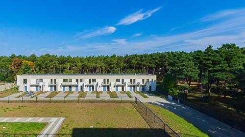 ein großes weißes Gebäude mit Bäumen im Hintergrund in der Unterkunft VacationClub - Marina Rogowo Apartament 91 in Rogowo