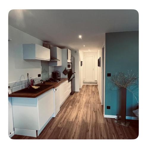 une cuisine avec des armoires blanches et un plancher en bois dans l'établissement Appartement tout confort climatisé, à Saint-Uze