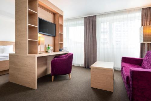 a hotel room with a bed and a purple chair at Stadthotel am Römerturm in Cologne