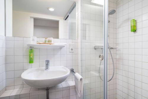 Un baño blanco con lavabo y ducha. en Stadthotel am Römerturm, en Colonia