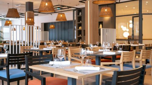 a restaurant with wooden tables and chairs and lights at Hotel Pelegrin Plava Laguna in Umag