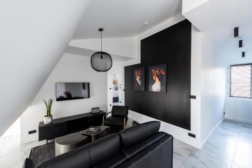 ein Wohnzimmer mit einer schwarzen Couch und einem Fernseher in der Unterkunft O'Lord, 4 Etoiles, Residence de Luxe Champs-Elysees in Paris