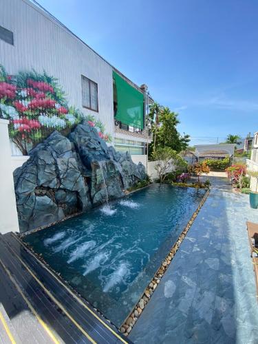 a swimming pool with a waterfall in front of a building at Eco Bliss Hotel in Thôn Lại Thê
