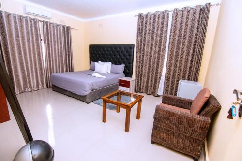 a bedroom with a bed and a chair and a table at Luxe Countryside Convention Center in Livingstone
