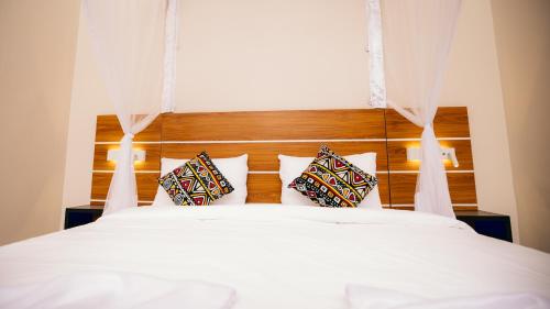 Un dormitorio con una cama blanca con dos almohadas. en Migano Residence, en Buyumbura