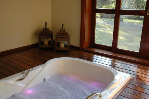a bath tub in a room with a window at Canto da Floresta Ecoresort in Amparo