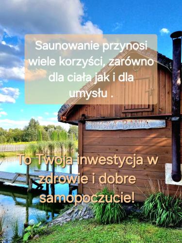 a sign in front of a lake with a building at Dworek Mieldziczowka in Supraśl