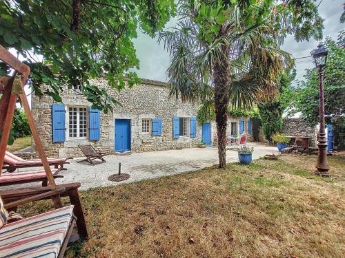 a stone house with blue doors and a palm tree at Holiday Home Petichaud by Interhome in Saint-Sulpice-dʼArnoult