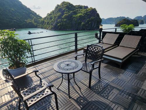 a balcony with chairs and a table and a view of the water at Venus Cruises Halong Bay in Ha Long