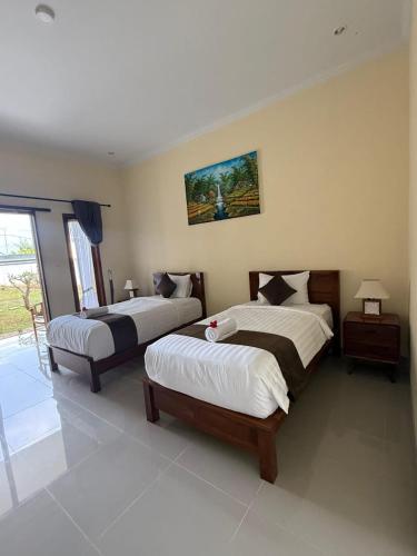 a bedroom with two beds and a window at D'vayana Nusa Hotel in Nusa Penida