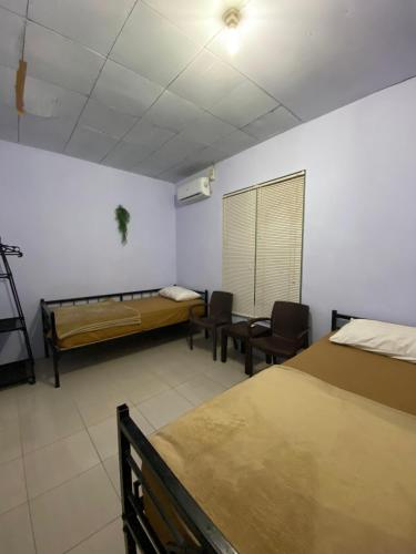 a room with two beds and chairs and a window at Neo Robiu & Ijen Tour in Banyuwangi
