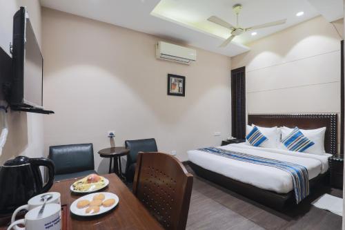 a hotel room with a bed and a table with a plate of food at Cosy Grand, Chanakyapuri by The Cosy Hotels in New Delhi