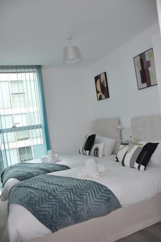 two large beds in a room with windows at Modern 2-Bed Apartment, The Hub MK, Free Parking & Smart TV in Milton Keynes