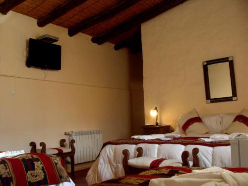 a bedroom with two beds and a tv on the wall at Hotel Norte Rupestre in Tilcara