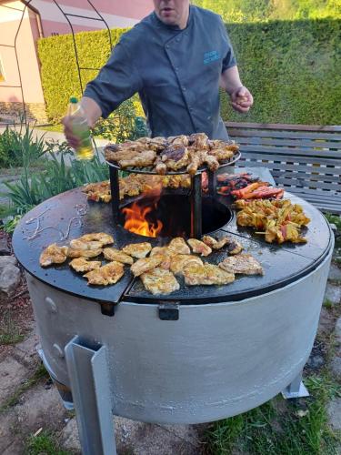 a man is cooking food on a grill at Pension Bílý Hořec in Vrchlabí