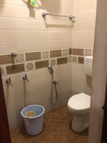 a bathroom with a toilet and a bucket in it at FERDIN COTTAGE in Kanyakumari
