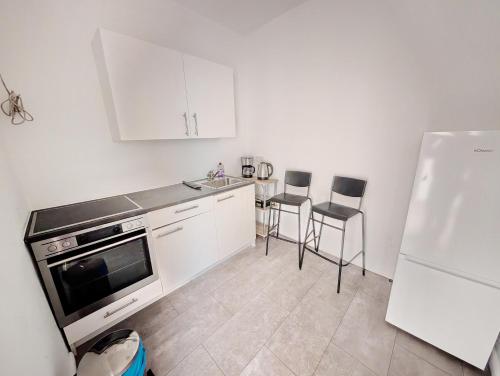 Lovely Rooms in Märzstraße Area MZ49 في فيينا: مطبخ بخزائن بيضاء ومغسلة وثلاجة