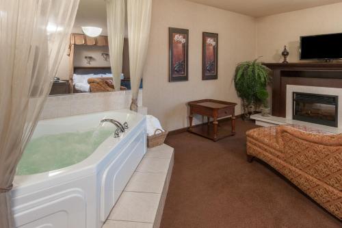 a living room with a bath tub and a fireplace at Ramada by Wyndham Drumheller Hotel & Suites in Drumheller