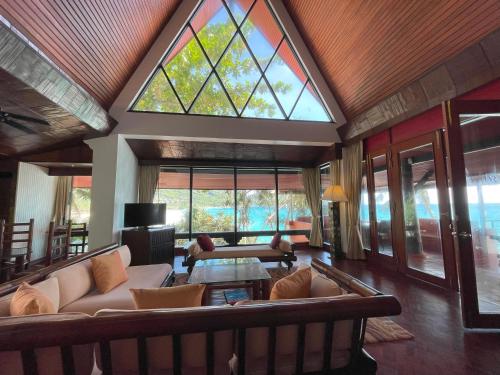 a large living room with a large window and couches at Mom Tri's Villa Royale - SHA Plus in Kata Beach