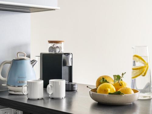 a counter with a bowl of oranges and cups on it at Numa Munich Viktoria in Munich