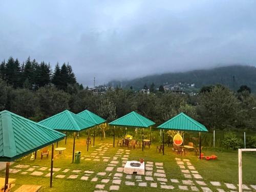 a group of tables and umbrellas in a field at Hotel Celebriti Inn by London vista Hotels - Old Manali in Manāli