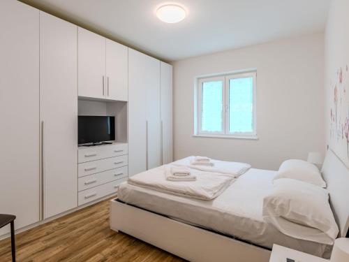 a white bedroom with a bed and a tv at Apartment Calicantus by Interhome in Dro