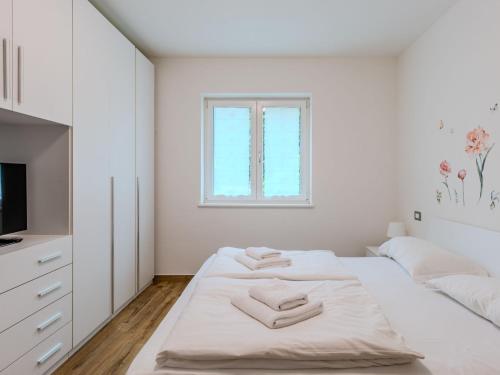 a white bedroom with a bed and a window at Apartment Calicantus by Interhome in Dro