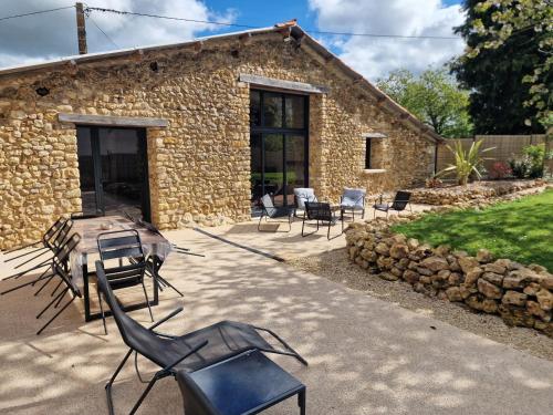 a stone house with chairs and a grill in front of it at L'Escale Nobilienne in Nouaillé-Maupertuis