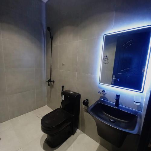 a bathroom with a black toilet and a sink at منتجع هدب للشقق المخدومة in Taif