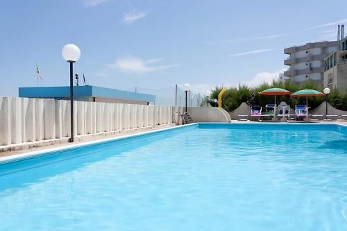 a large blue swimming pool with chairs and umbrellas at Hotel Leonardo da Vinci in Pesaro