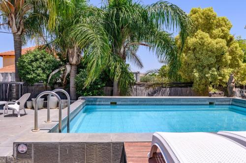 a swimming pool in a yard with palm trees at בקתות ילוז של רשת לב הגולן - 6 צימרים מקסימים עם בריכה משותפת ליד הכנרת in Yavneʼel