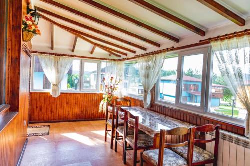 a dining room with a table and chairs and windows at Cozy Villa Retreat in Cigov Chark in Tsigov Chark
