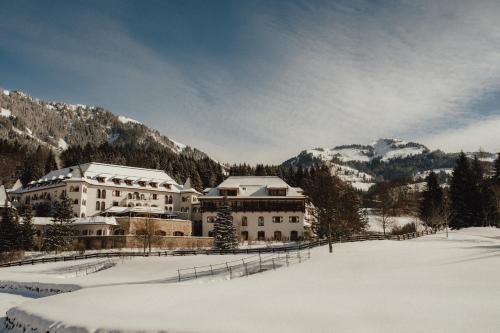 a large building in the snow in front of mountains at Schlosshotel Kitzbühel in Kitzbühel