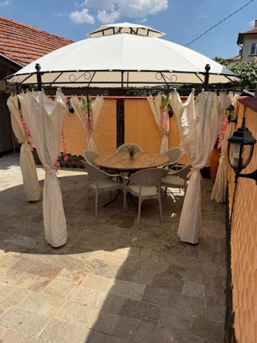 a wooden table under an umbrella in a patio at Къща за гости Леон in Belogradchik