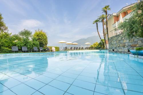 a swimming pool at a resort with chairs and umbrellas at Bellavista Swiss Quality Hotel in Vira