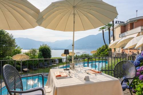 a dining table with umbrellas and a view of the water at Bellavista Swiss Quality Hotel in Vira