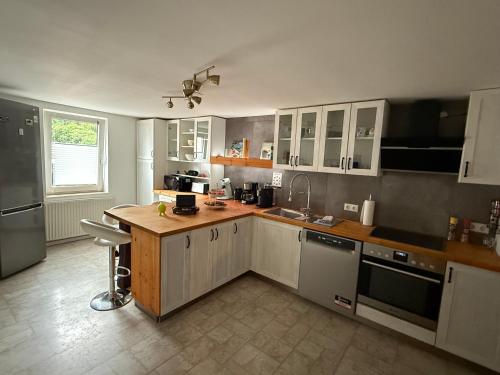 a kitchen with white cabinets and a wooden counter top at Mühlenzauber Hameln in Hessisch Oldendorf