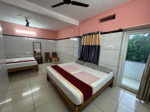 a bedroom with two beds and a window at Ashirvad Residency in Bhatkal