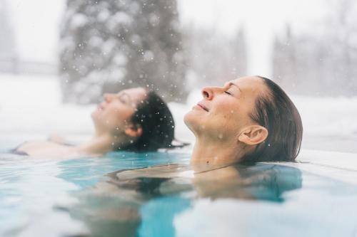 two women in a swimming pool in the rain at Schlosshotel Kitzbühel in Kitzbühel